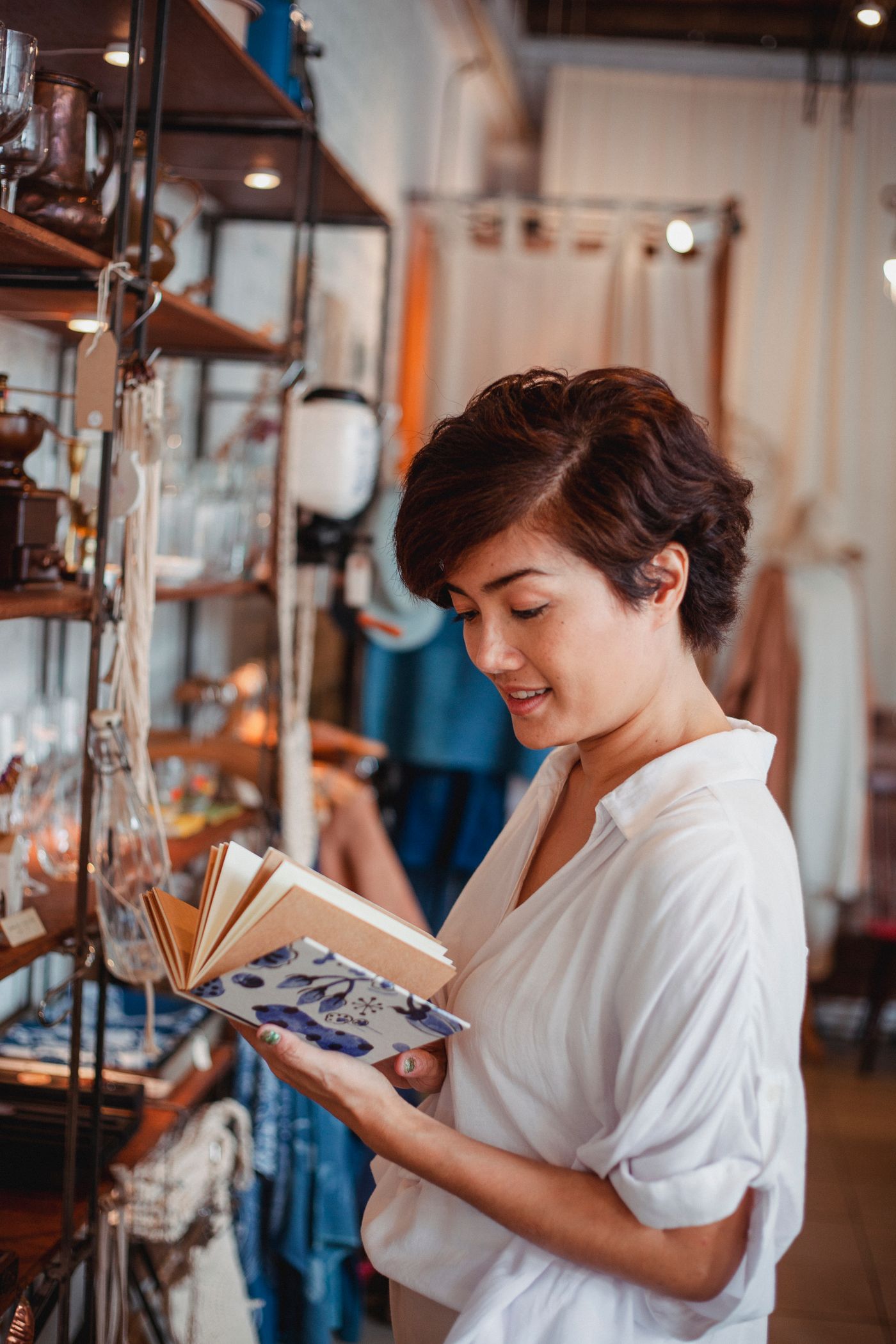 Vrouw met een notitieboek bij kledingrekken