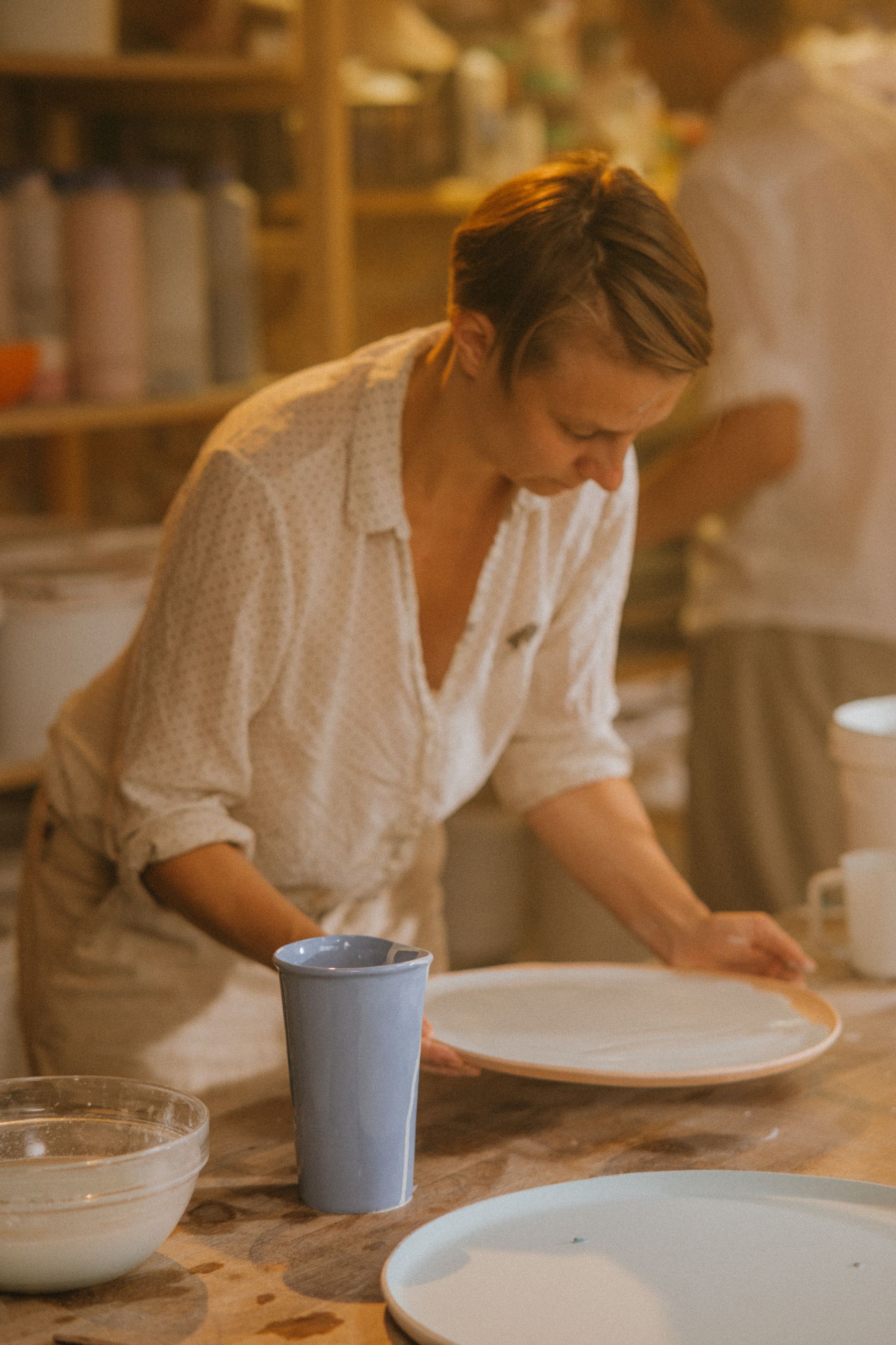 Een keramiste werkt aan een bord in haar atelier
