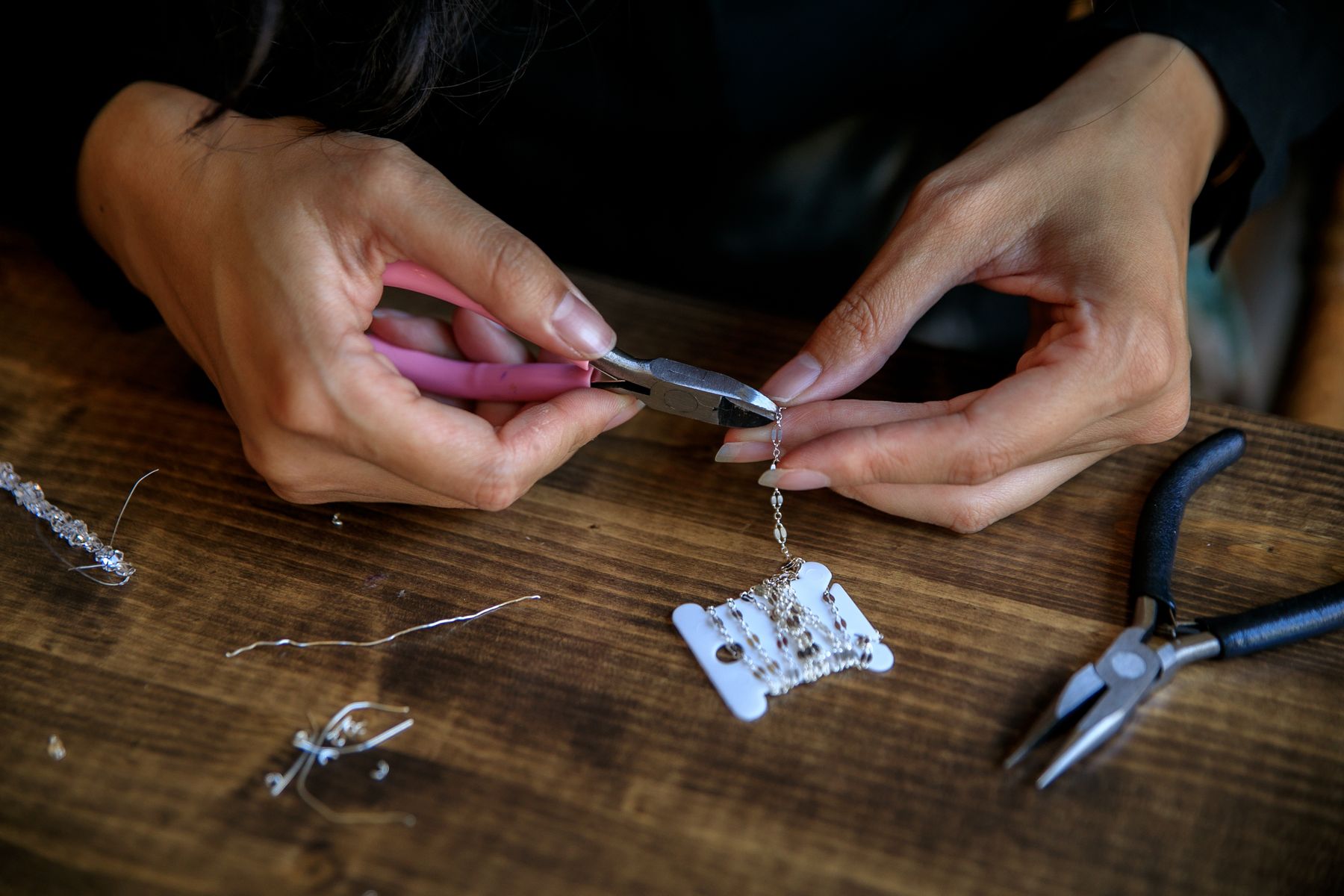 Een maker werkt met een tang aan een sieraad op de werktafel