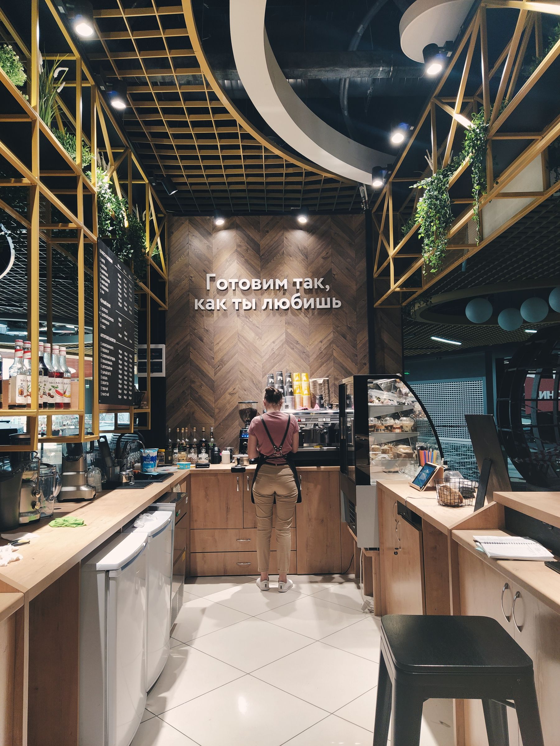 Een koffiebar met een medewerker, toonbank en warme verlichting