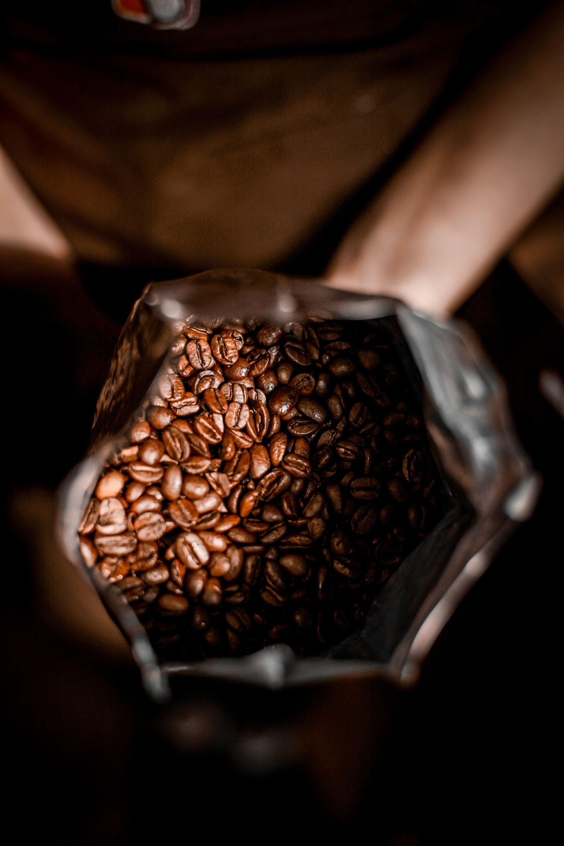Handen houden een geopende zak koffiebonen vast