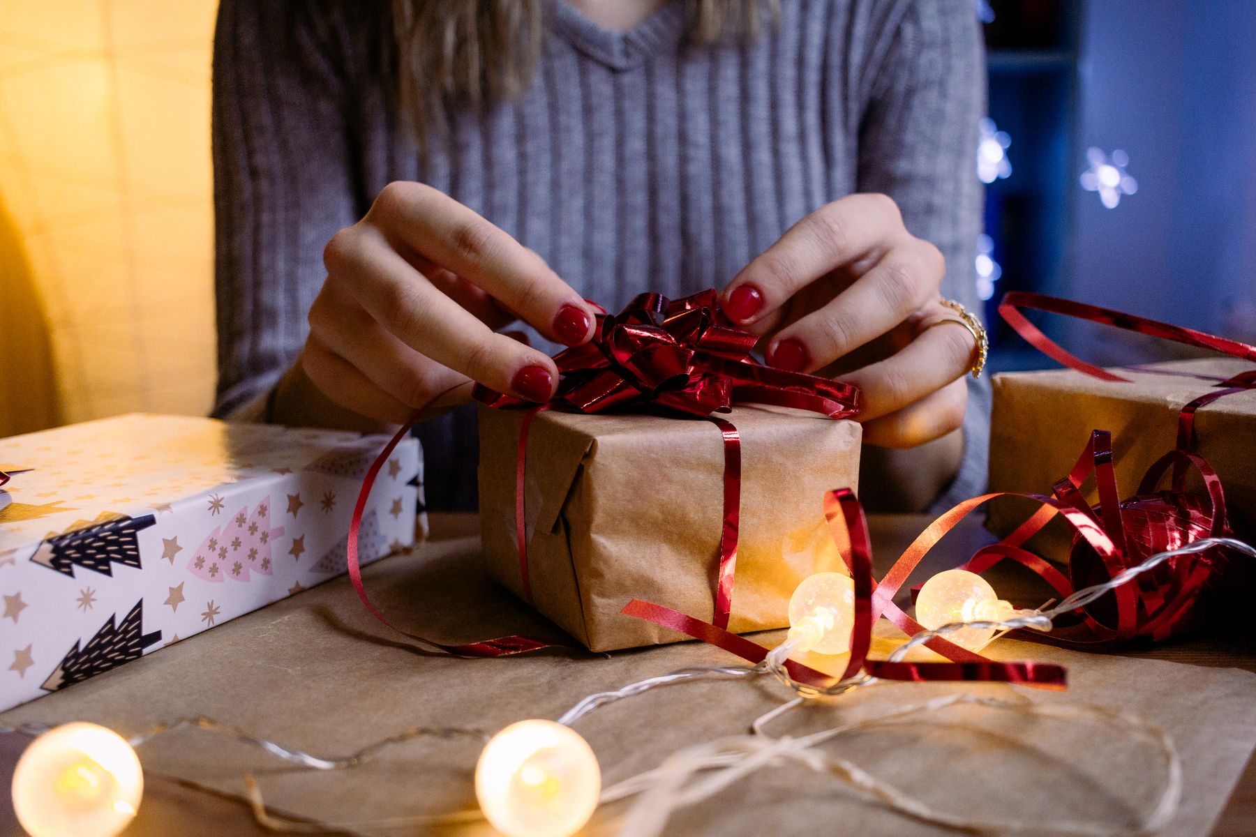 Handen verpakken een cadeau met rood lint