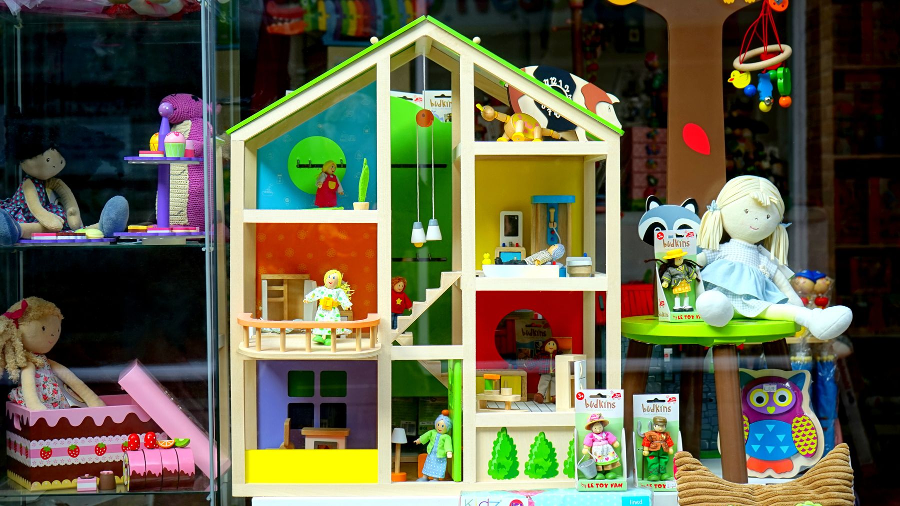Een houten poppenhuis en speelgoed in een etalage