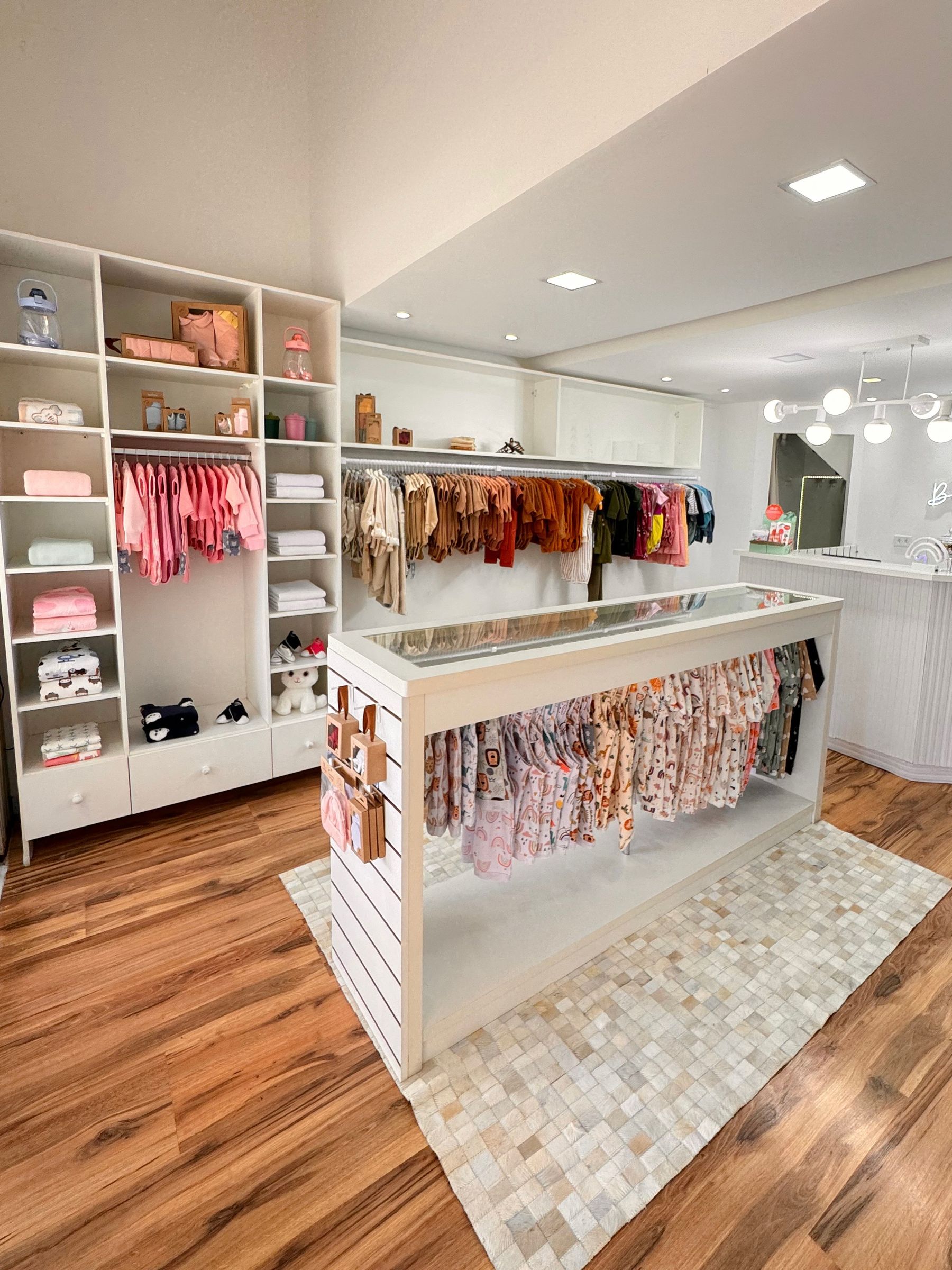 Een lichte kinderwinkel met kledingrekken en houten planken