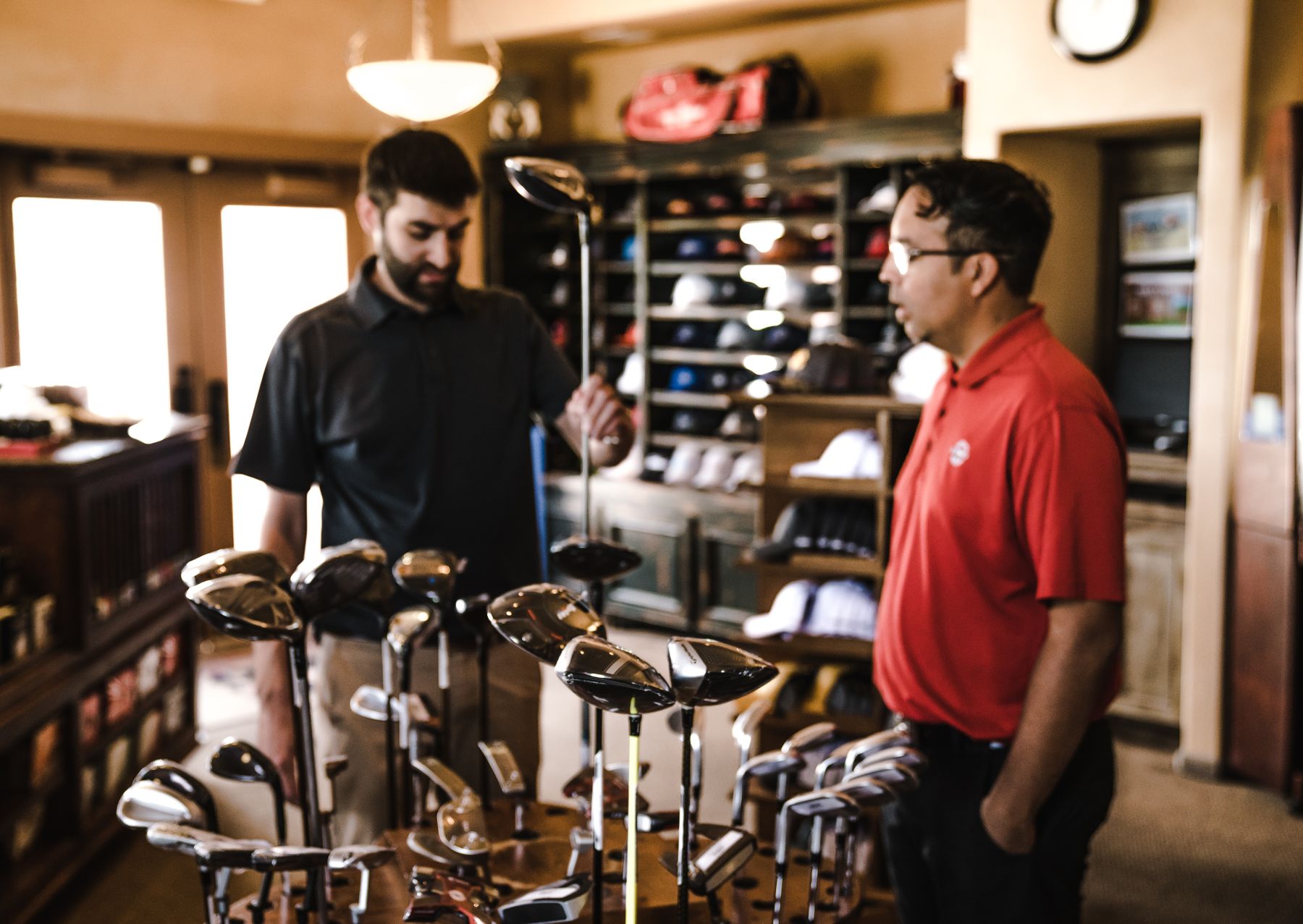 Een medewerker en klant bekijken golfclubs in een sportwinkel