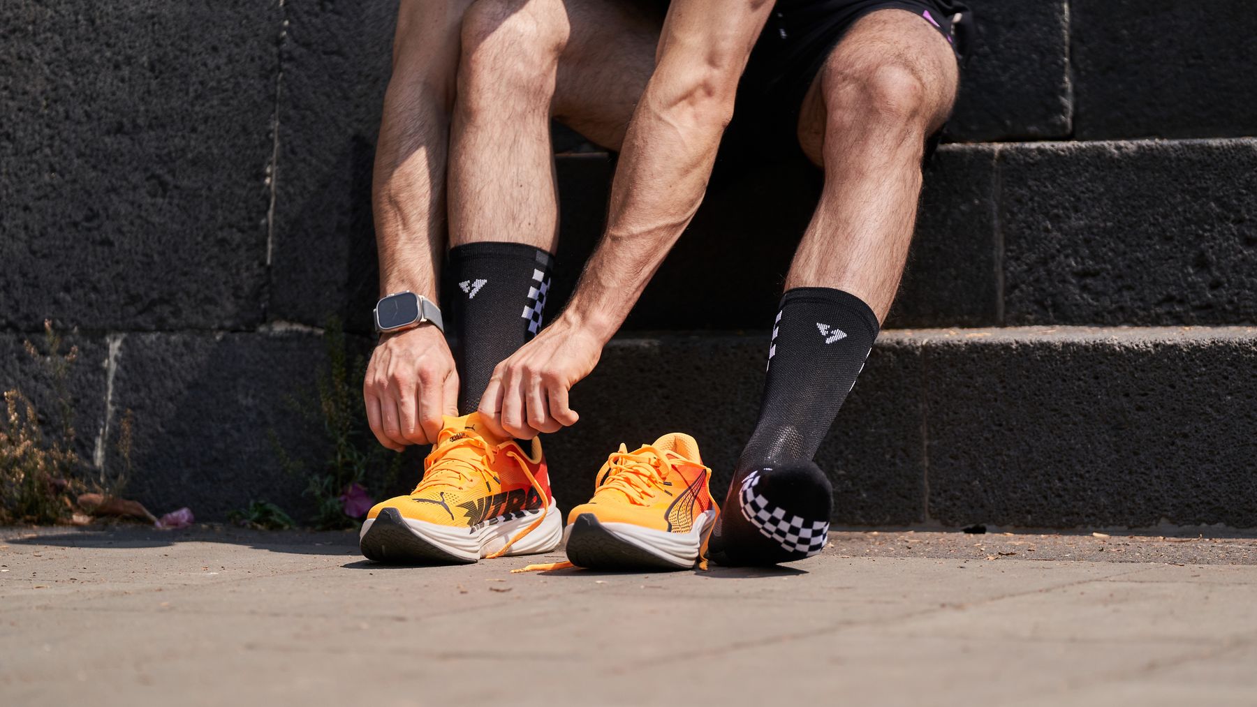 Een hardloper strikt oranje schoenen op een buitentrap