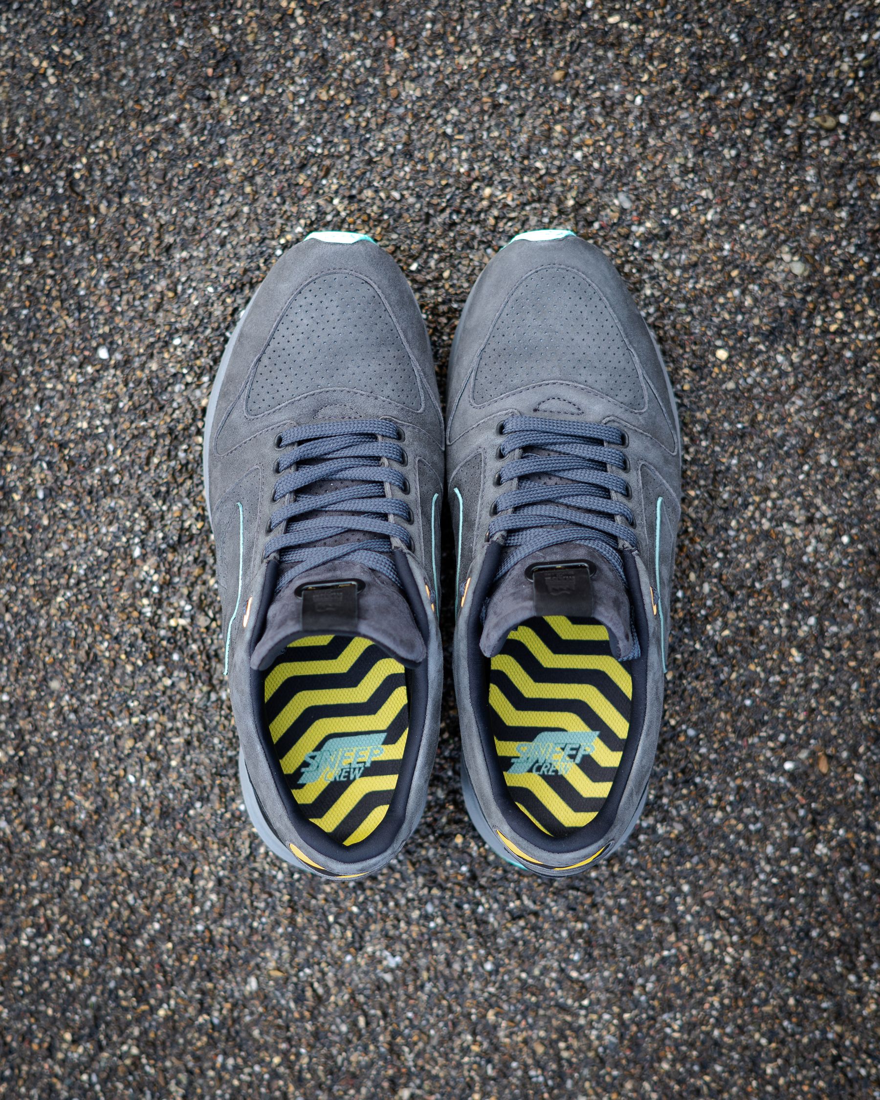 Grijze sportschoenen van bovenaf op een grindpad