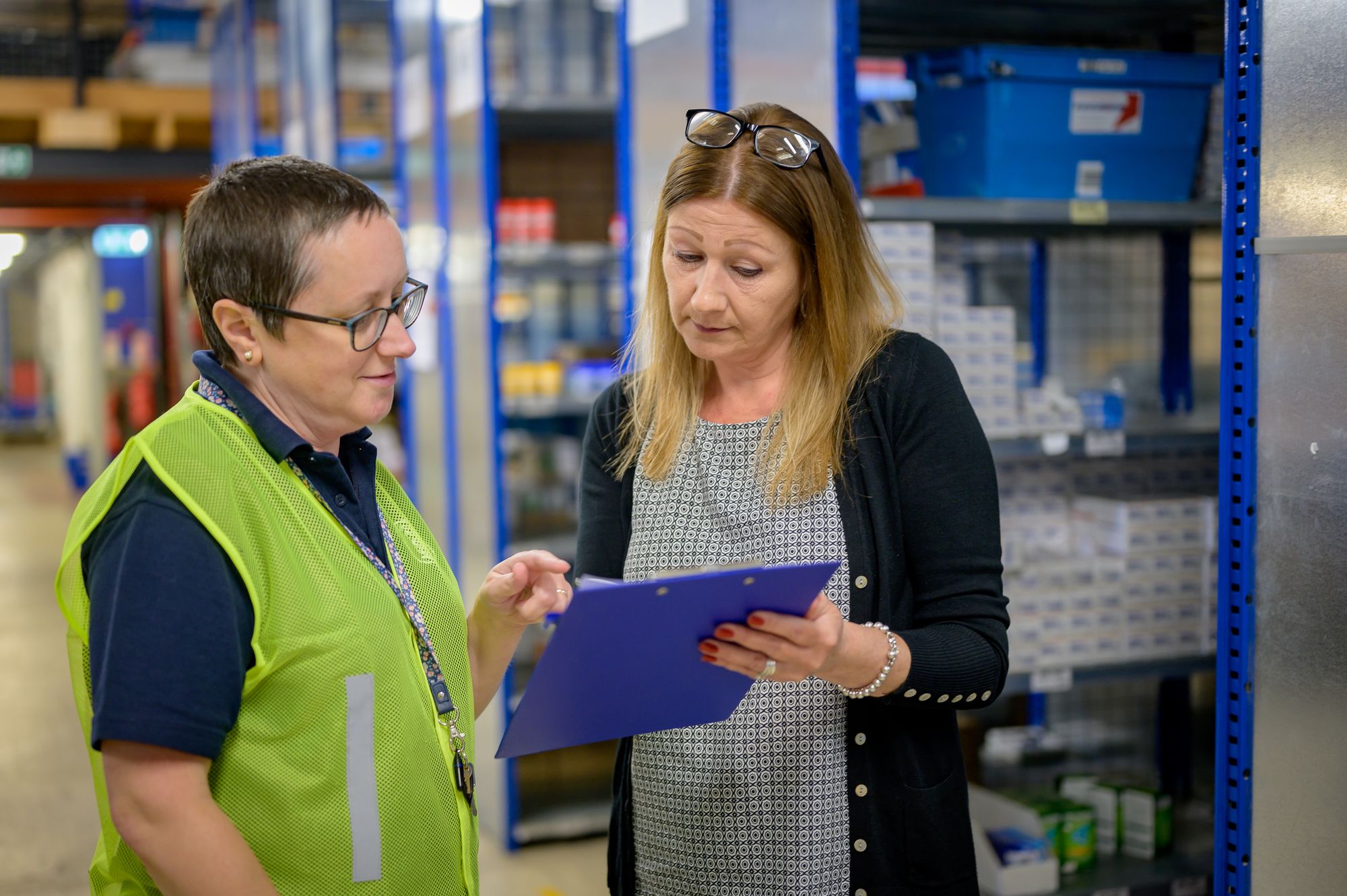 Twee medewerkers bespreken een voorraadlijst in een magazijn