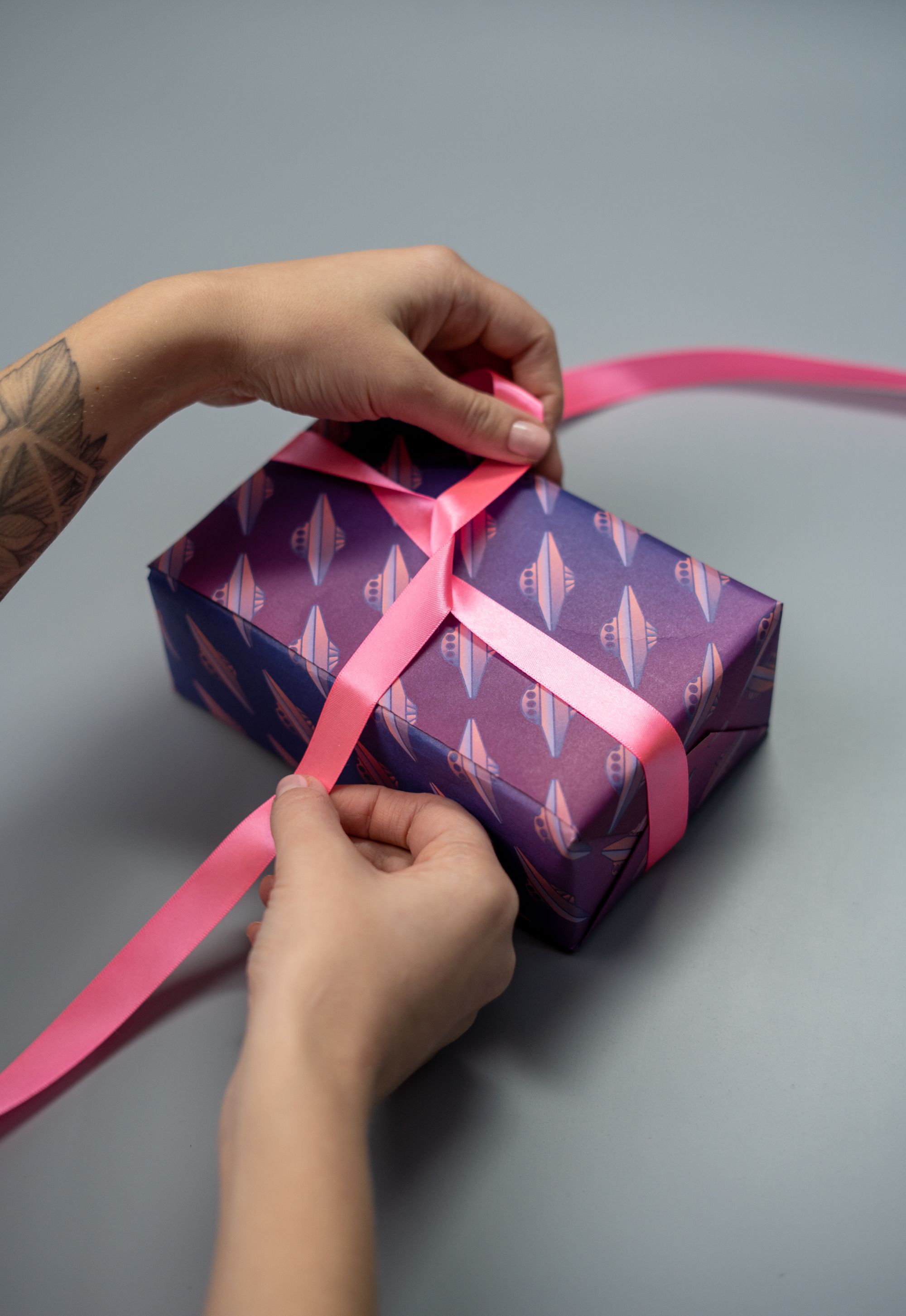 Handen strikken een roze lint om een cadeau