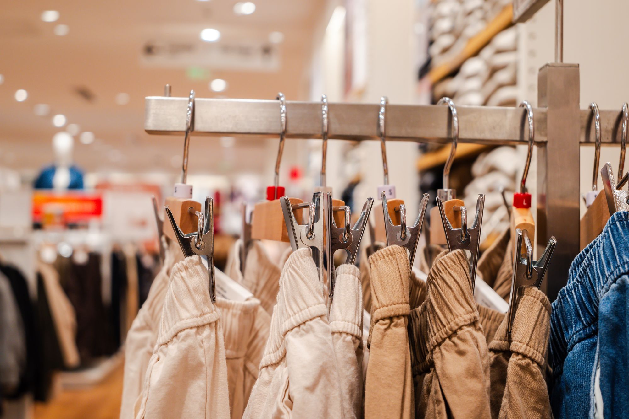 Detail van broeken aan hangers in een winkel