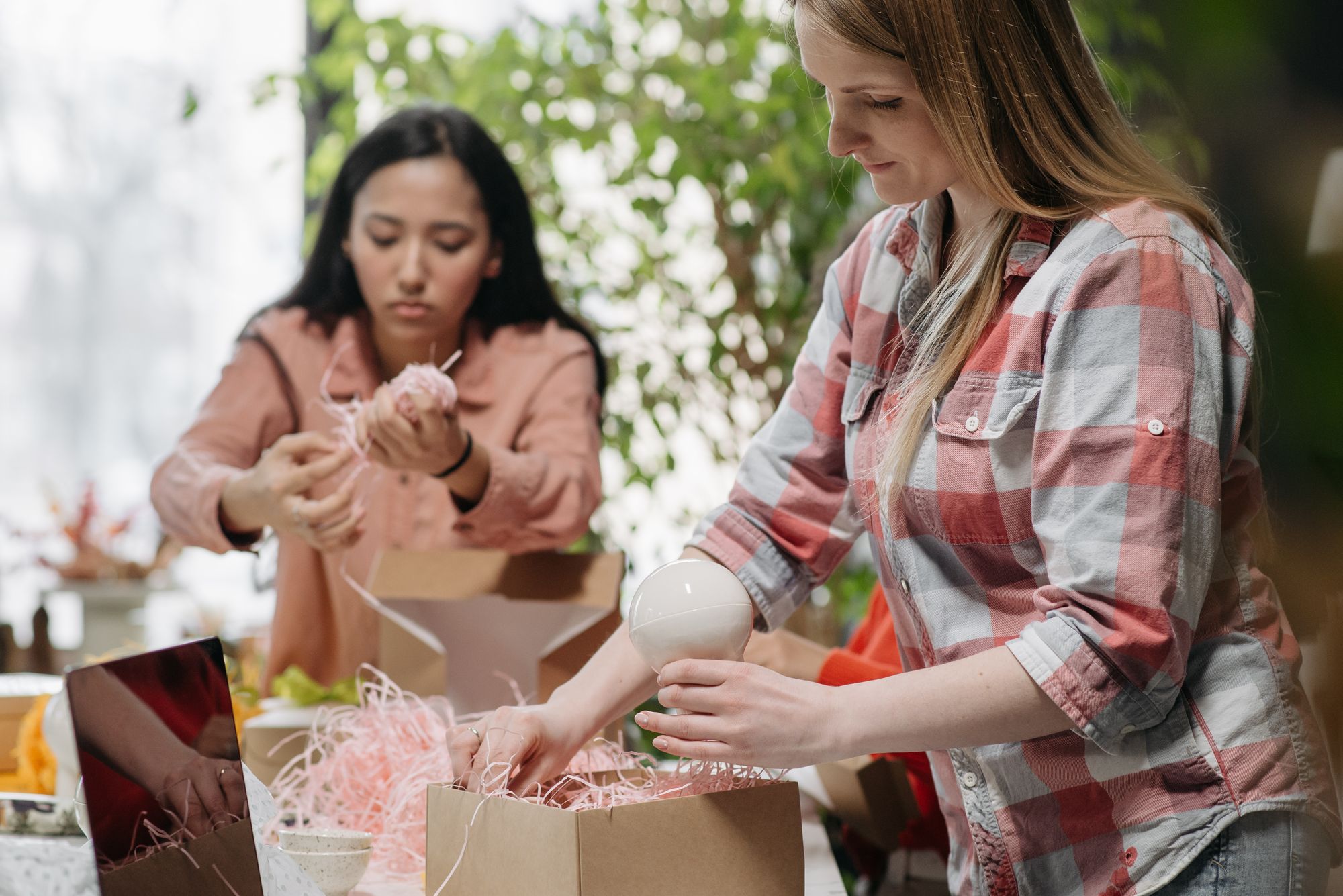Twee vrouwen pakken producten in kartonnen dozen